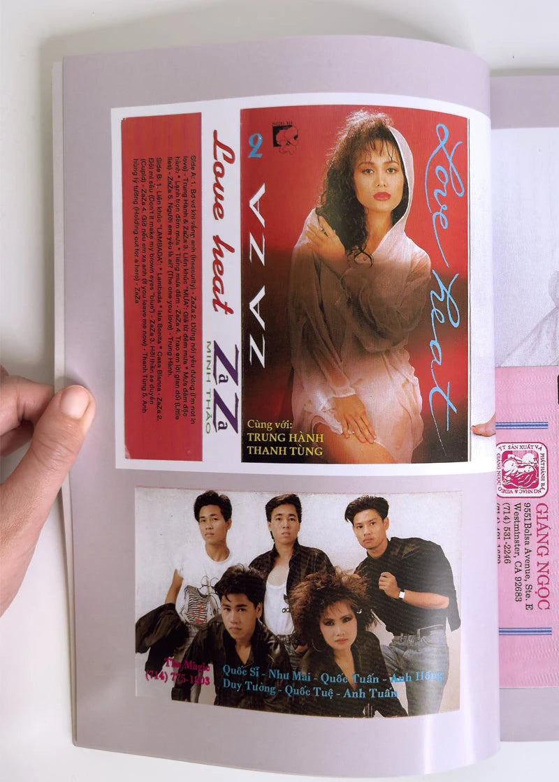 Vintage album or magazine with a cover featuring a woman and a group of people, held open by a hand.